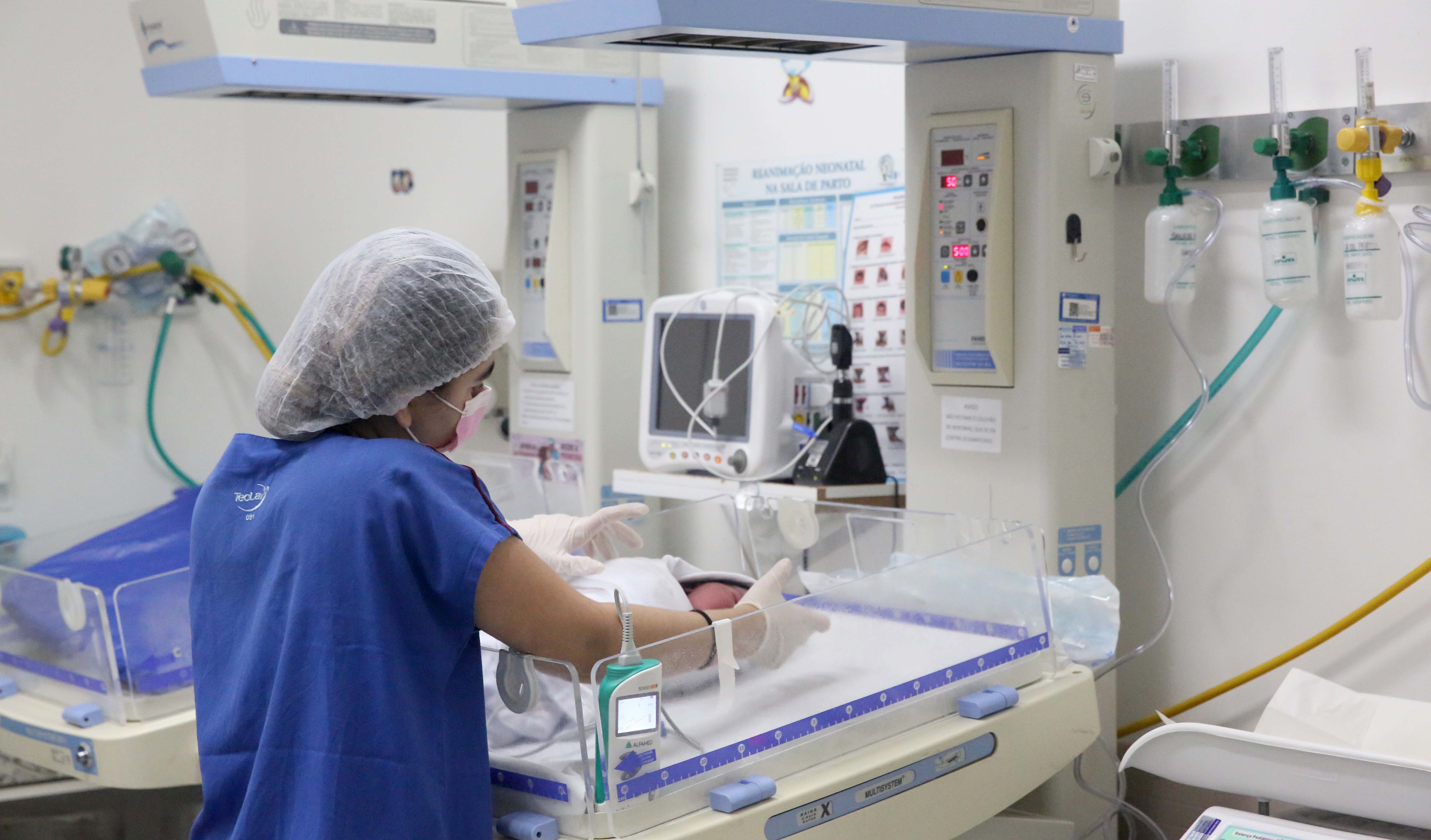 enfermeira segura um bebê dentro de uma UTI neonatal